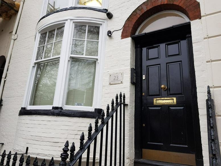 Exterior of 23 Grand Parade, Brighton, East Sussex featuring a black door and large bay window.
