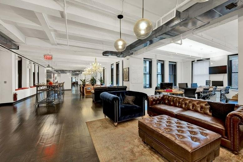 Spacious communal lounge at 23 Great Titchfield Street featuring leather sofas and exposed ductwork.