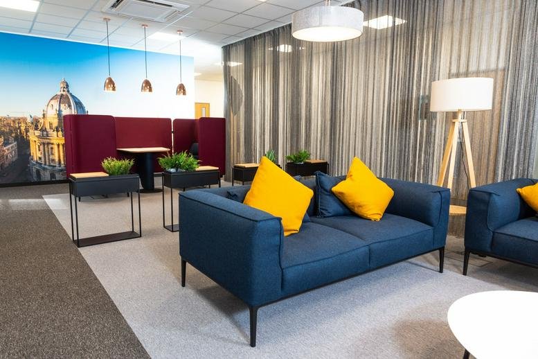 Spacious lounge at 234 Botley Road, Oxford with blue sofas, yellow cushions, and a scenic city mural.