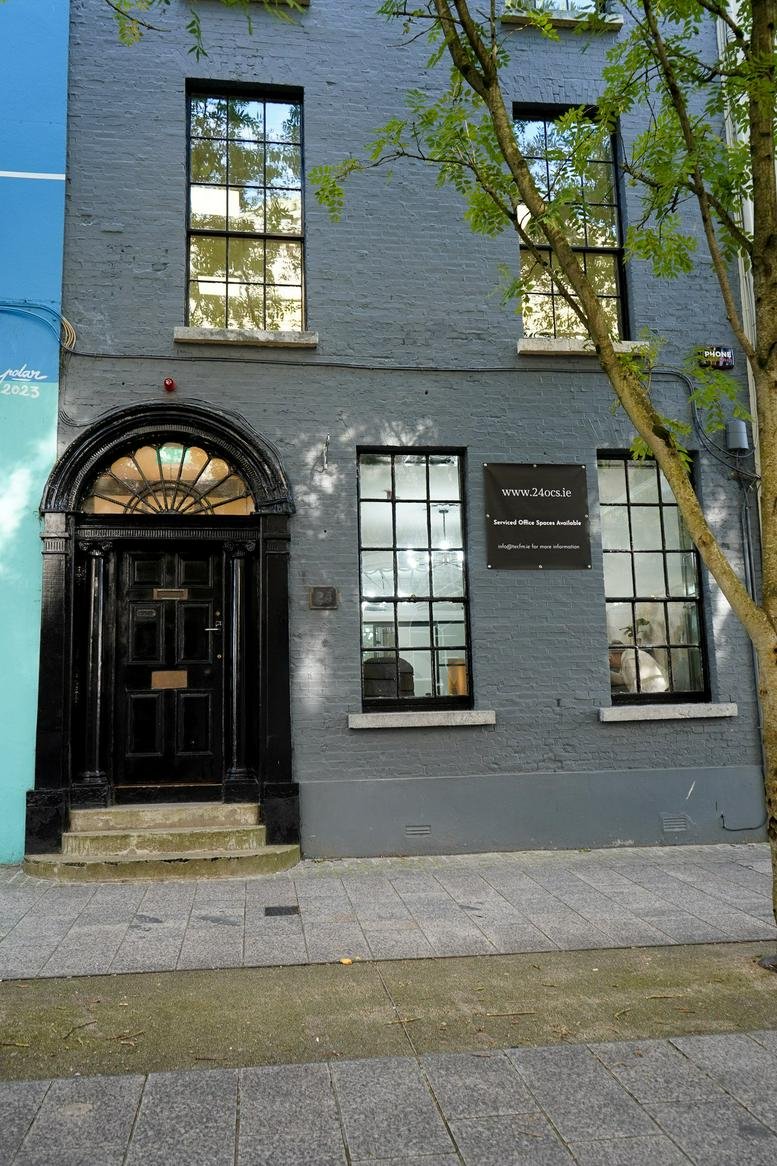Grey exterior building facade of 24 O’Connell Street, Waterford with a black arched doorway.