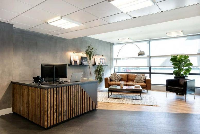 Wooden slatted reception desk at 25 Procter Street, 4th Floor, London with a leather sofa and plants.