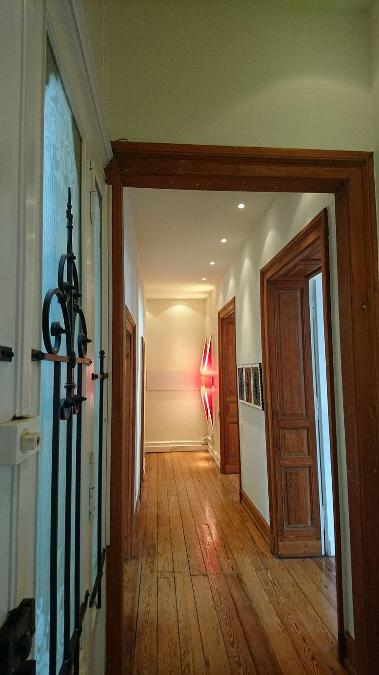 Entryway with ornate wrought iron glass doors opening into a sunlit corridor.