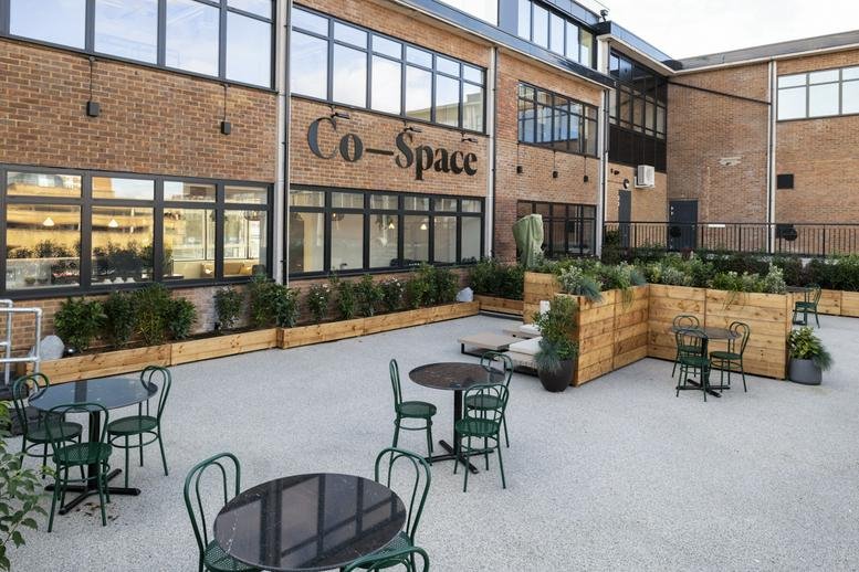 Building exterior of Co-Space at 25 Town Square featuring brickwork and an outdoor patio with seating.