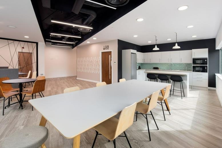 Spacious communal breakout area with a large dining table and modern kitchen.