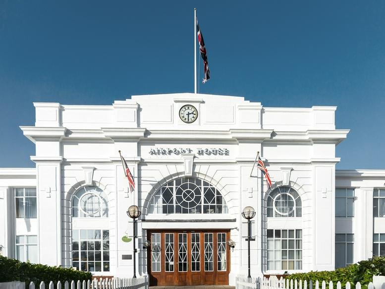 Grand historic white exterior of Croydon Airport Airport House with its iconic clock and flagpoles.