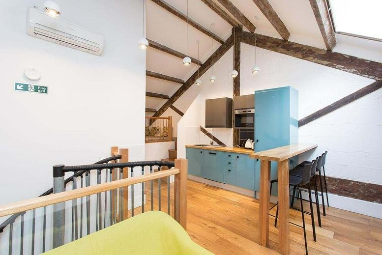 Modern loft kitchen with blue cabinetry and exposed wooden beams at 27 Corsham St, Hoxton, London.