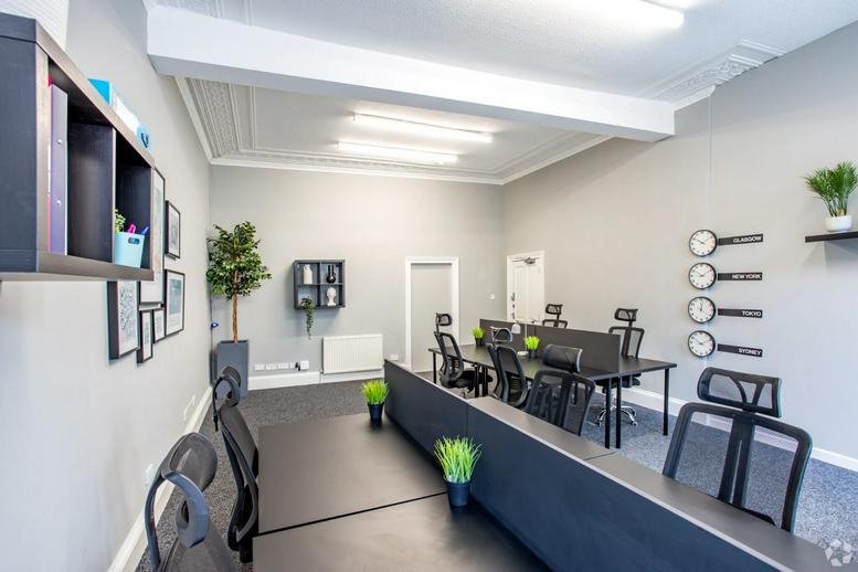 Workspace with rows of black desks, ergonomic chairs, and wall clocks.
