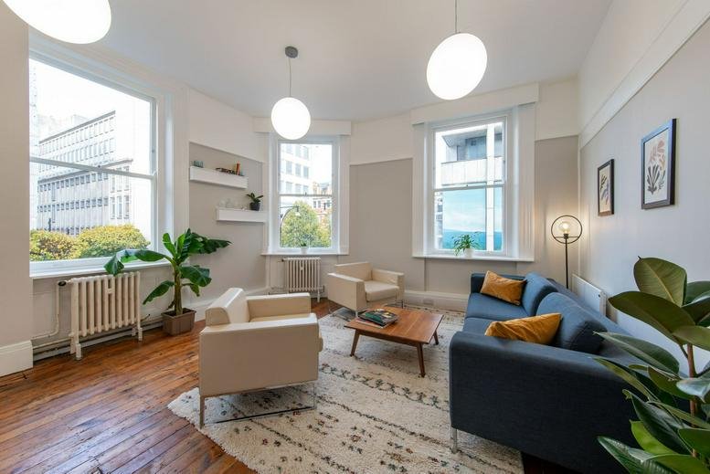 Spacious lounge at 30 Binney Street, Mayfair, London with blue sofa, white armchairs, and large windows.
