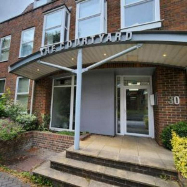 Exterior entrance of 30 The Courtyard featuring a curved metal canopy and brick facade.