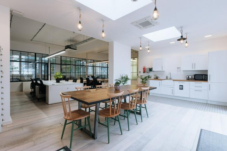 Spacious communal kitchen and dining area at 32-38 Scrutton Street with hanging industrial lights.