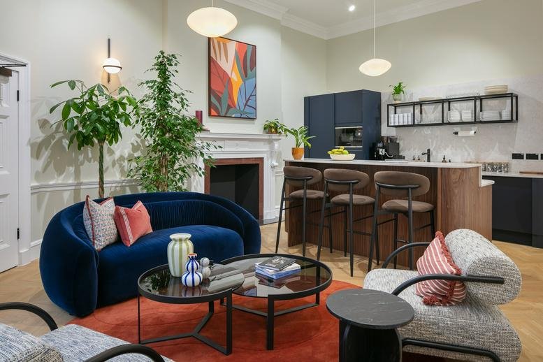 Spacious communal lounge at 32 Welbeck Street with a blue velvet sofa, fireplace, and breakfast bar.