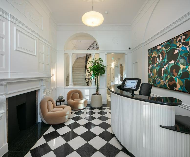 Reception area at 32 Welbeck Street featuring a curved white desk and checkered floor.