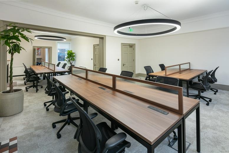 Open-plan workspace with long timber desks and ergonomic black chairs.