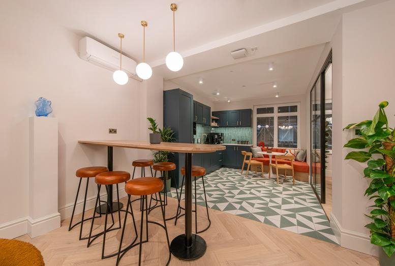 Spacious communal breakout area at 321 Oxford Street with high-top seating and patterned tile flooring.