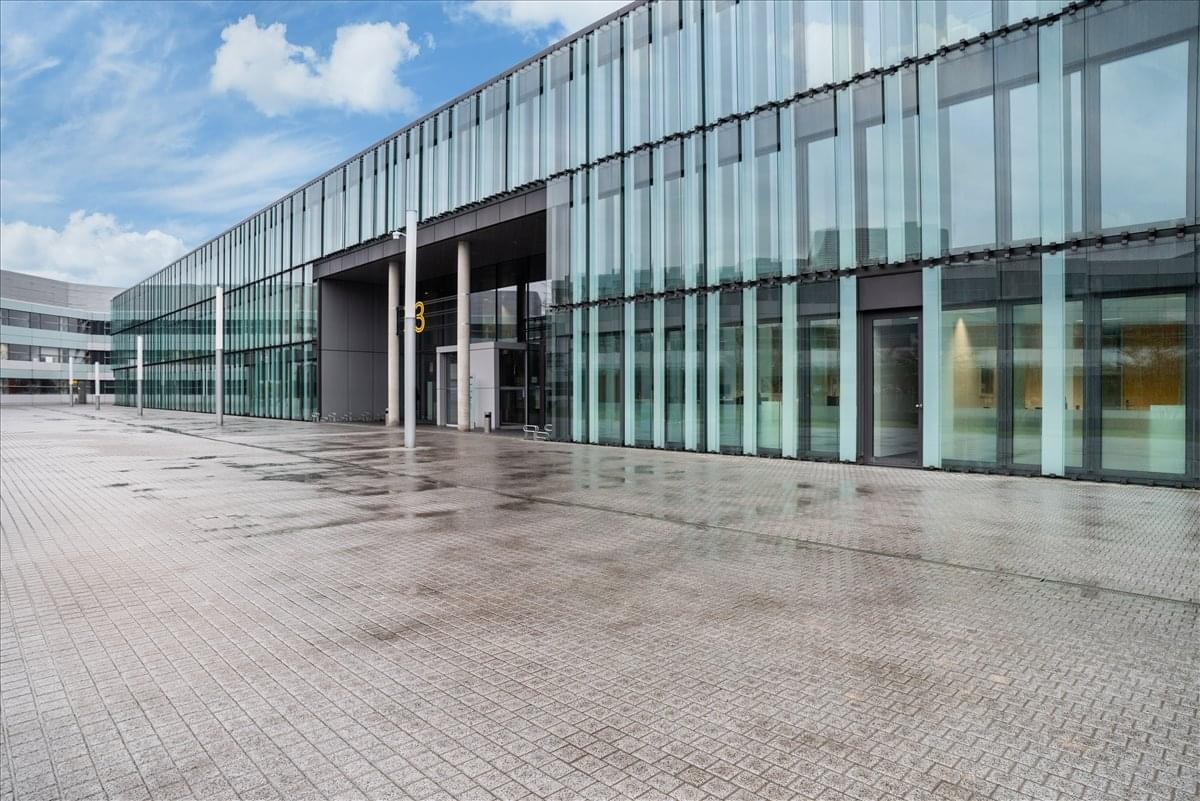 Exterior view of the modern glass-facade building at 33, 39, rue du Puits Romain.