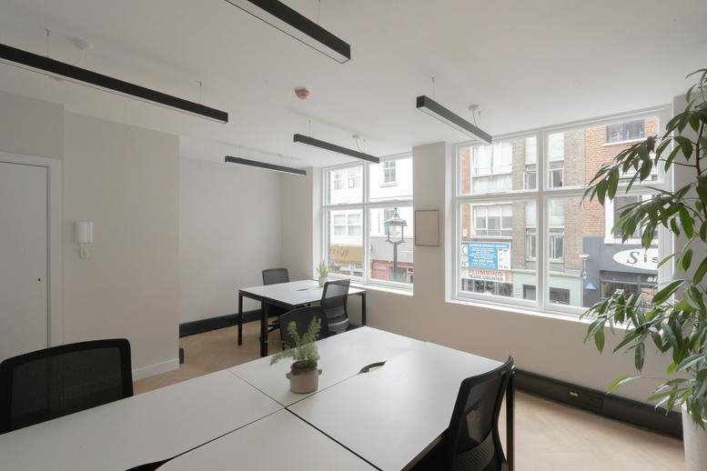 Spacious open-plan workspace at 34 – 35 Berwick Street featuring multiple white desks and large windows.