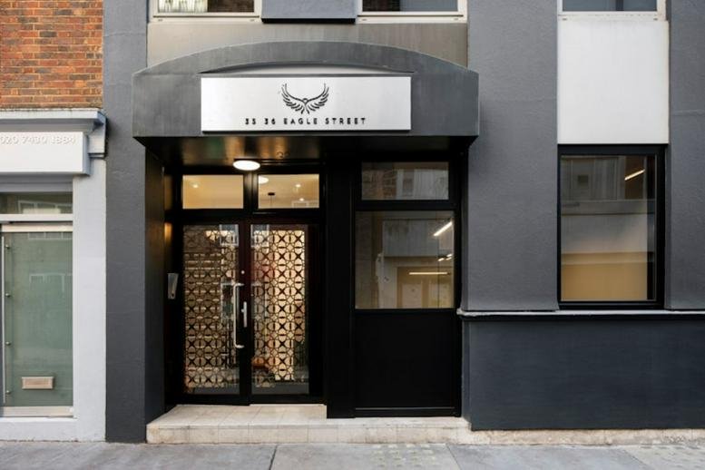 Exterior entrance of 35-36 Eagle Street, Adler House, showing a modern dark facade and lit doorway.