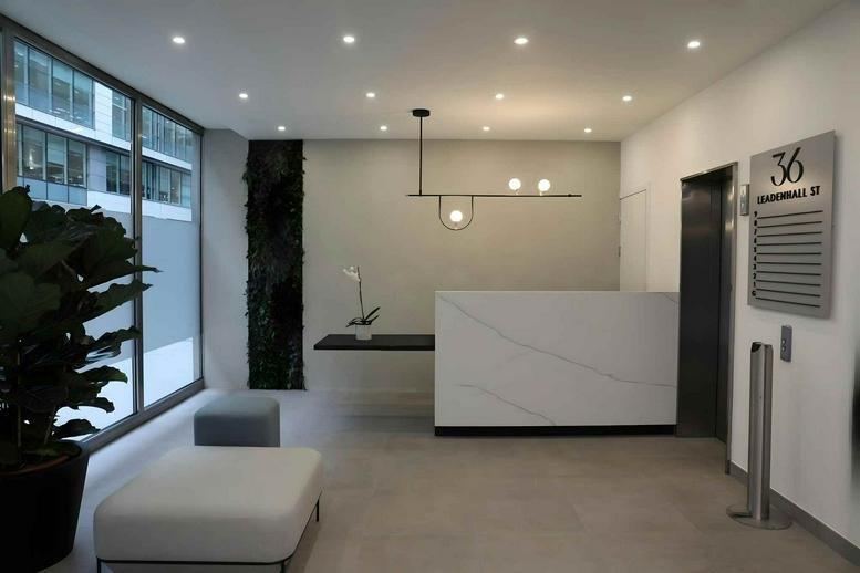 Minimalist white reception desk with a contemporary pendant light and green wall feature.