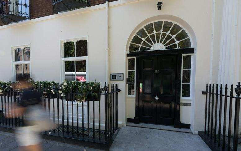 Exterior view of the white Georgian facade and black arched doorway at 36 Soho Square.