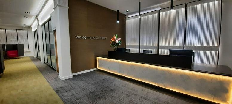 Reception area at 38, Queen Street, Glasgow with a stone-clad desk and warm accent lighting.