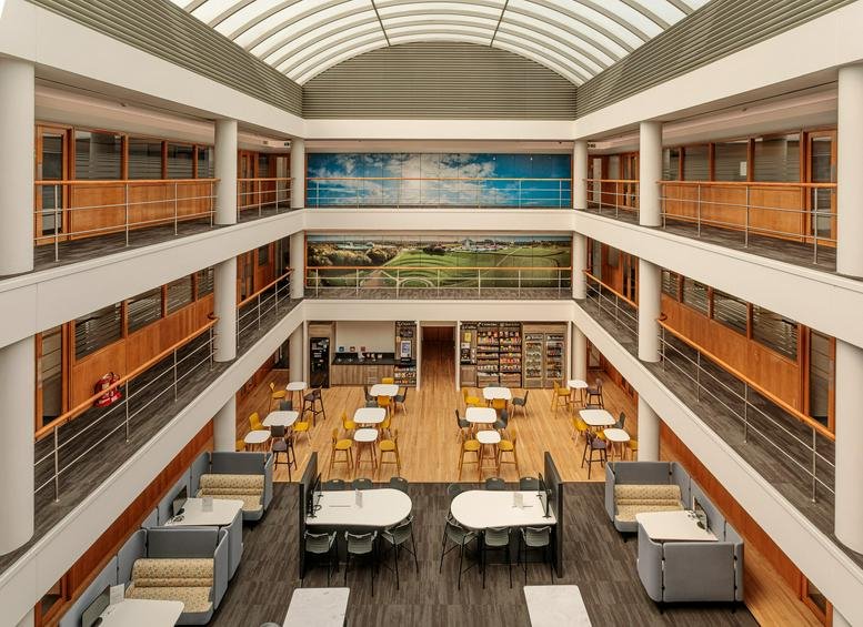 Wide view of a three-story atrium at 399 Silbury Boulevard with cafe seating and skylights.