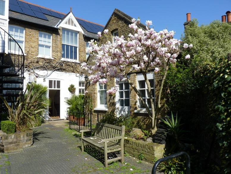 Exterior view of the brick building and flowering tree at 4 Evelyn Road, Chiswick, The Courtyard.