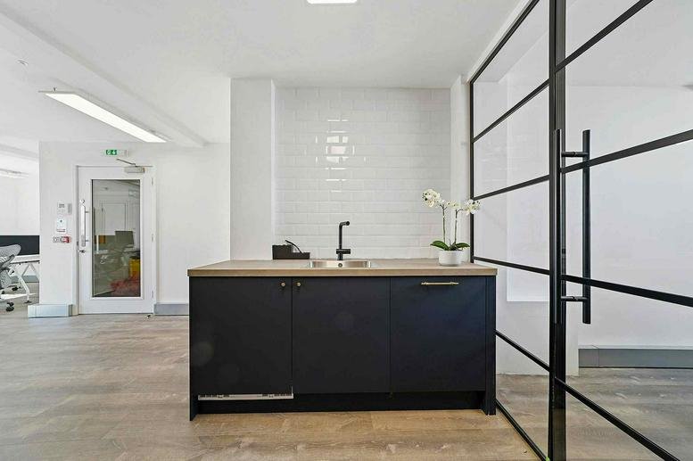 Sleek kitchenette with a black island and minimalist white tile backsplash.