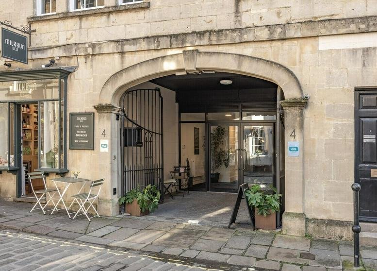 Exterior entrance of 4 Queen Street featuring a stone archway and outdoor seating.