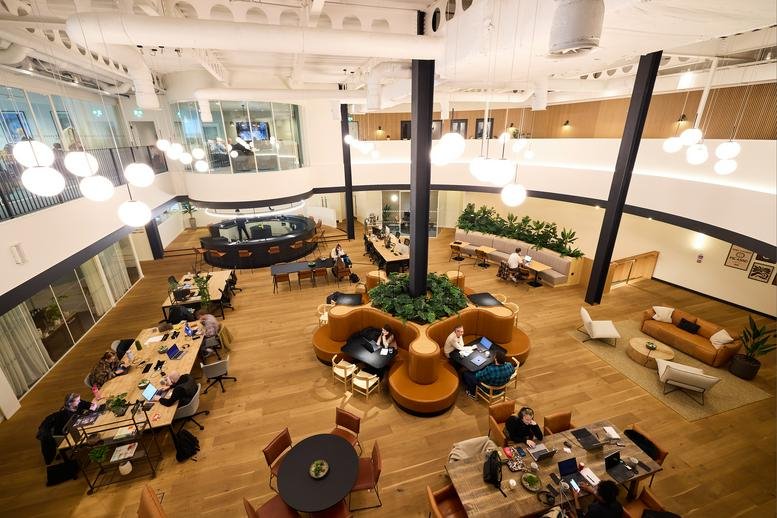Spacious communal coworking hub with warm wood floors and central greenery at 4 The Boulevard, Leeds Dock.