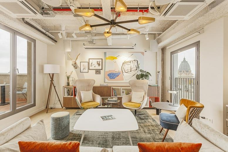 Spacious communal lounge at 40, Avinguda del Portal de l’Àngel, Barcelona with designer lighting and plush armchairs.