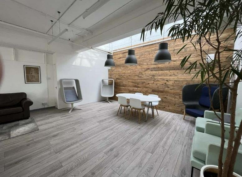 Spacious communal lounge featuring a wooden feature wall, dining table, and modern seating.