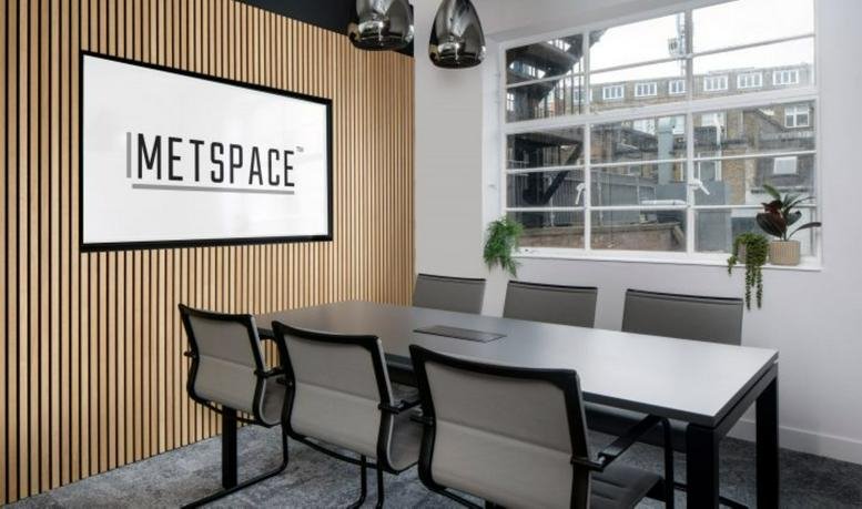 A professional meeting room at 43-45 Charlotte Street featuring wood slat walls and a wall-mounted screen.