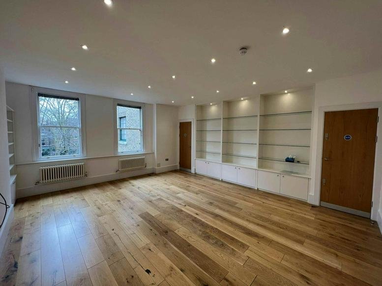 Spacious open-plan office at 44 Clerkenwell Close featuring warm wood floors and built-in shelving.