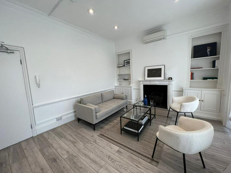 Spacious communal lounge with a grey sofa, white armchairs, and a fireplace at 440 Kings Road, London.