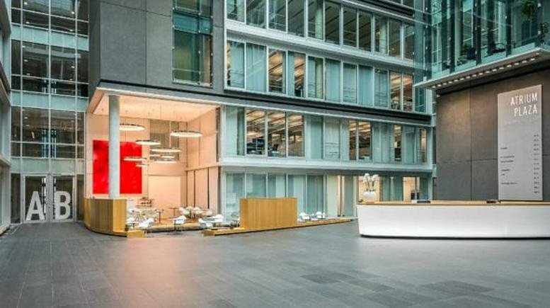 Bright, multi-story atrium at 45 Hindenburgstraße featuring a modern reception desk and lounge area.