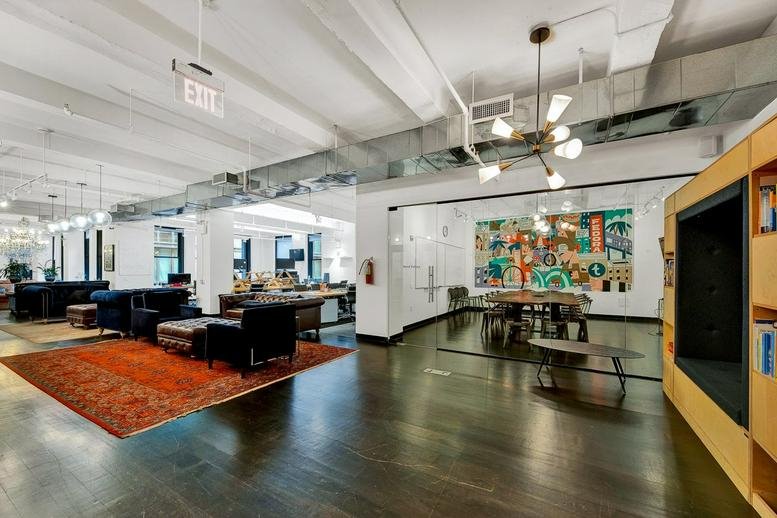 Spacious lounge at Floor 2, 45 Whitfield Street, Fitzrovia with polished wood floors and vibrant wall art.