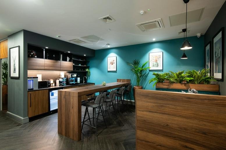 Spacious communal breakout area at 46 Park Place, Leeds with a wooden breakfast bar and teal feature wall.