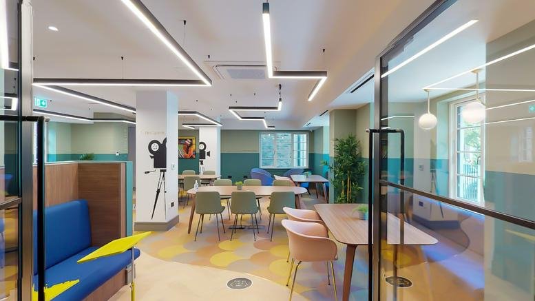 Colorful communal lounge with blue sofas, modern art, and zig-zag strip lighting at 49, Oxford Road, Finsbury Park.