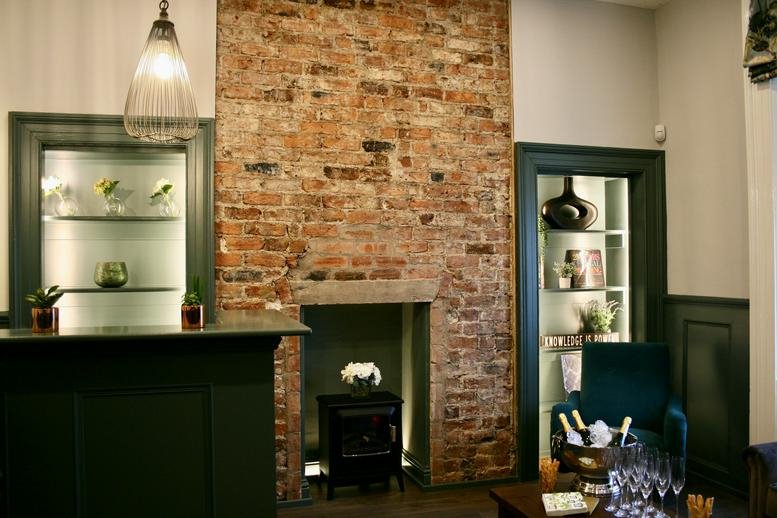 Characterful reception area at 5-6 Benton Terrace, Sandyford, with an exposed brick wall and dark green desk.