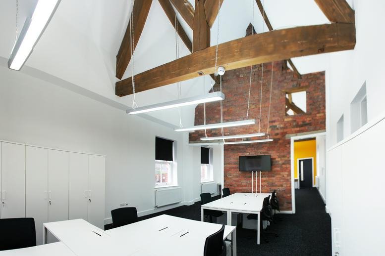 Spacious open-plan office at 5 Clock Tower Park with vaulted ceilings and exposed wooden beams.