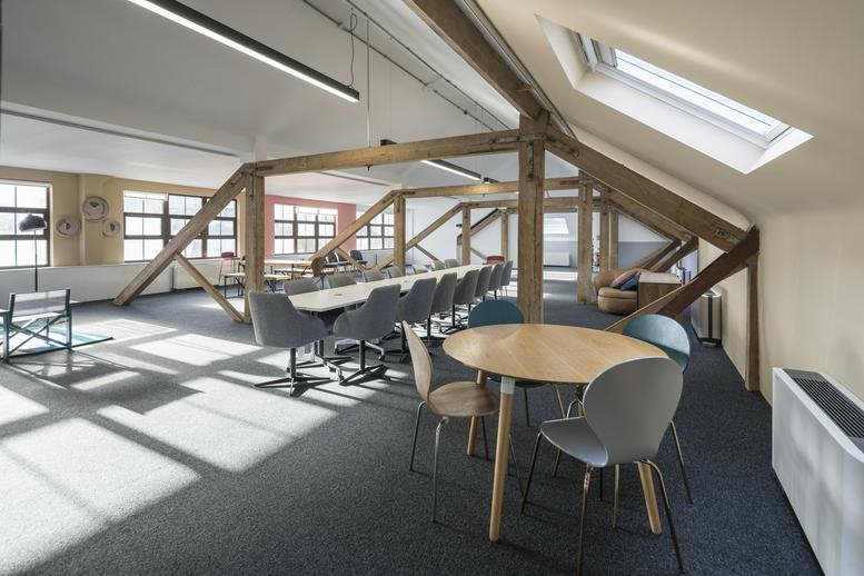 Bright attic workspace at 5, Singer Street featuring exposed timber beams, skylights, and a long meeting table.