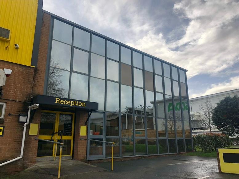 Exterior view of the glass-facade and yellow entrance at 5 Yeomans Way, Bournemouth.