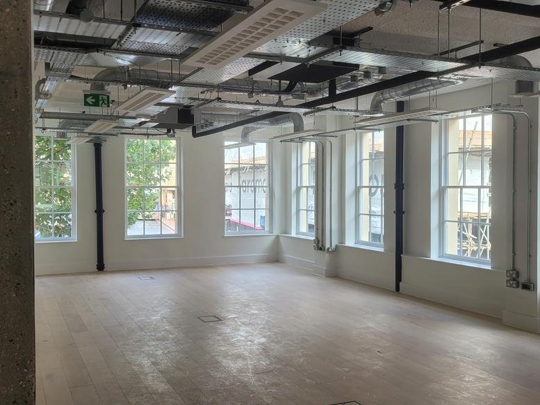 Spacious industrial-style open-plan office at 50, Market Place, Reading, Berkshire with large windows and exposed piping.