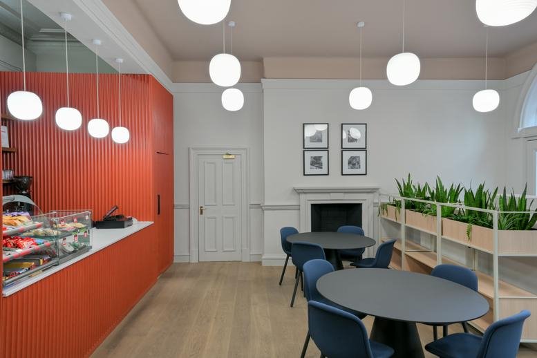 Colorful café and communal break area at 50 Wellington Street, Glasgow with orange walls and pendant lighting.