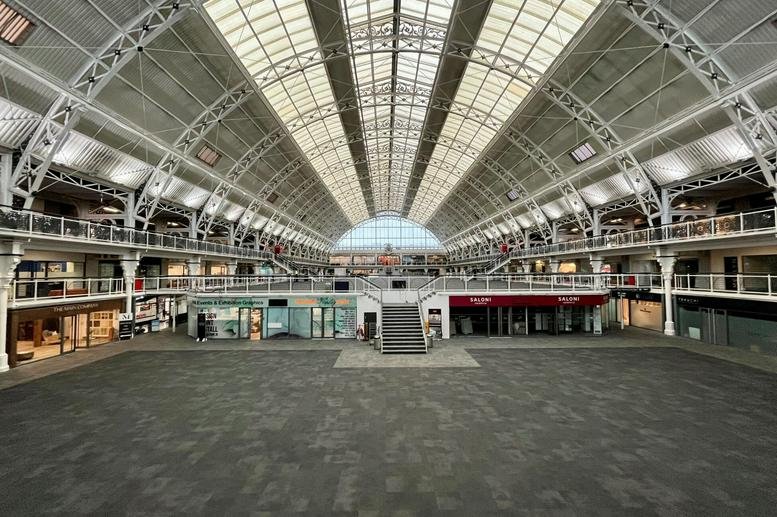 Grand communal hall under a massive barrel-vaulted glass roof with multi-level internal balconies.
