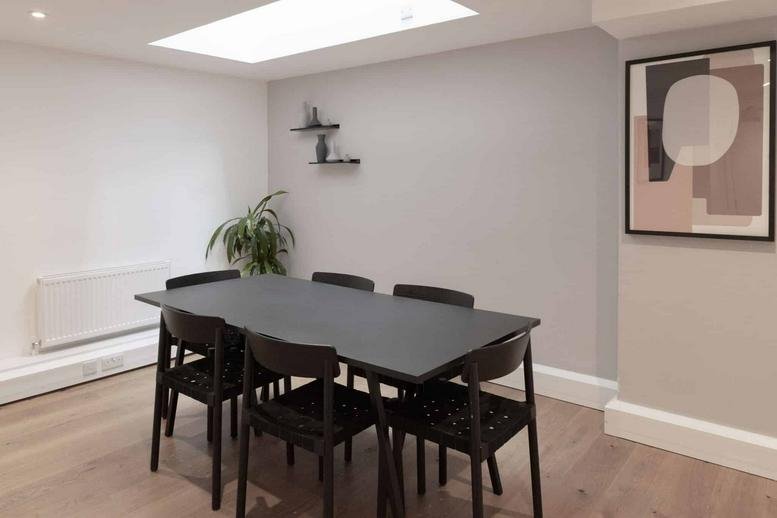 Spacious meeting room with a large dark table, black chairs, and a skylight.
