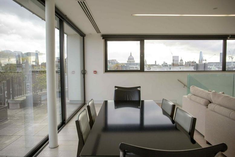 Formal boardroom with a dark reflective table and expansive views of the London skyline.
