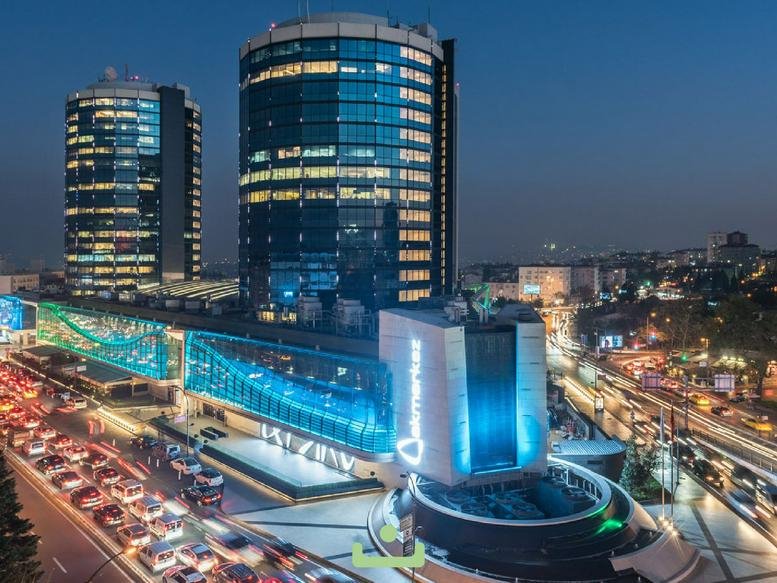 Evening exterior view of the glass-facade Nisbetiye Cd No: 54 building with vibrant blue lighting.