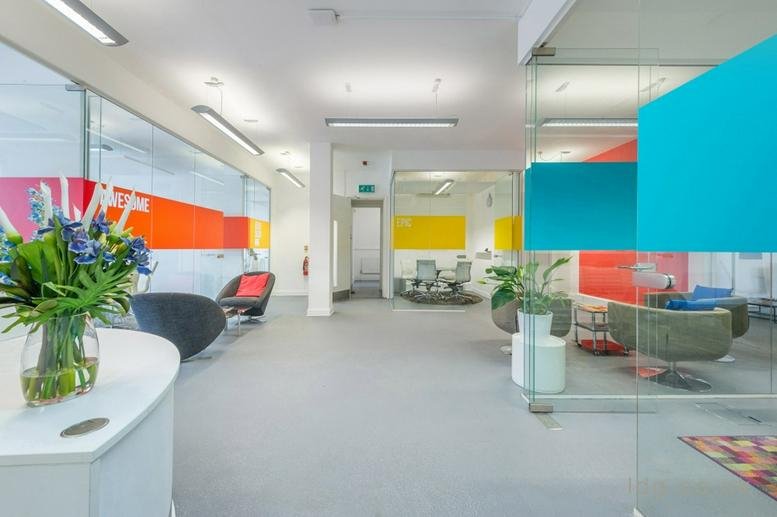 Bright reception area featuring colourful glass partitions in orange, yellow, and blue.