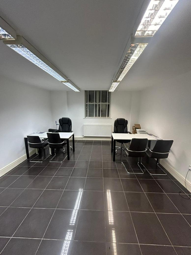Spacious office suite at 58-60, Alexandra Road, Enfield with two white desks and black chairs on dark tile floors.